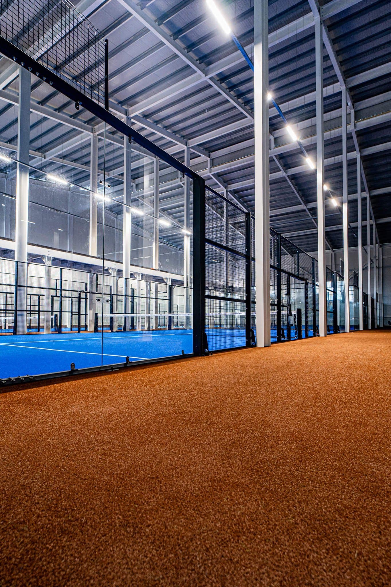 Steel columns and beams alongside an Evolve padel court